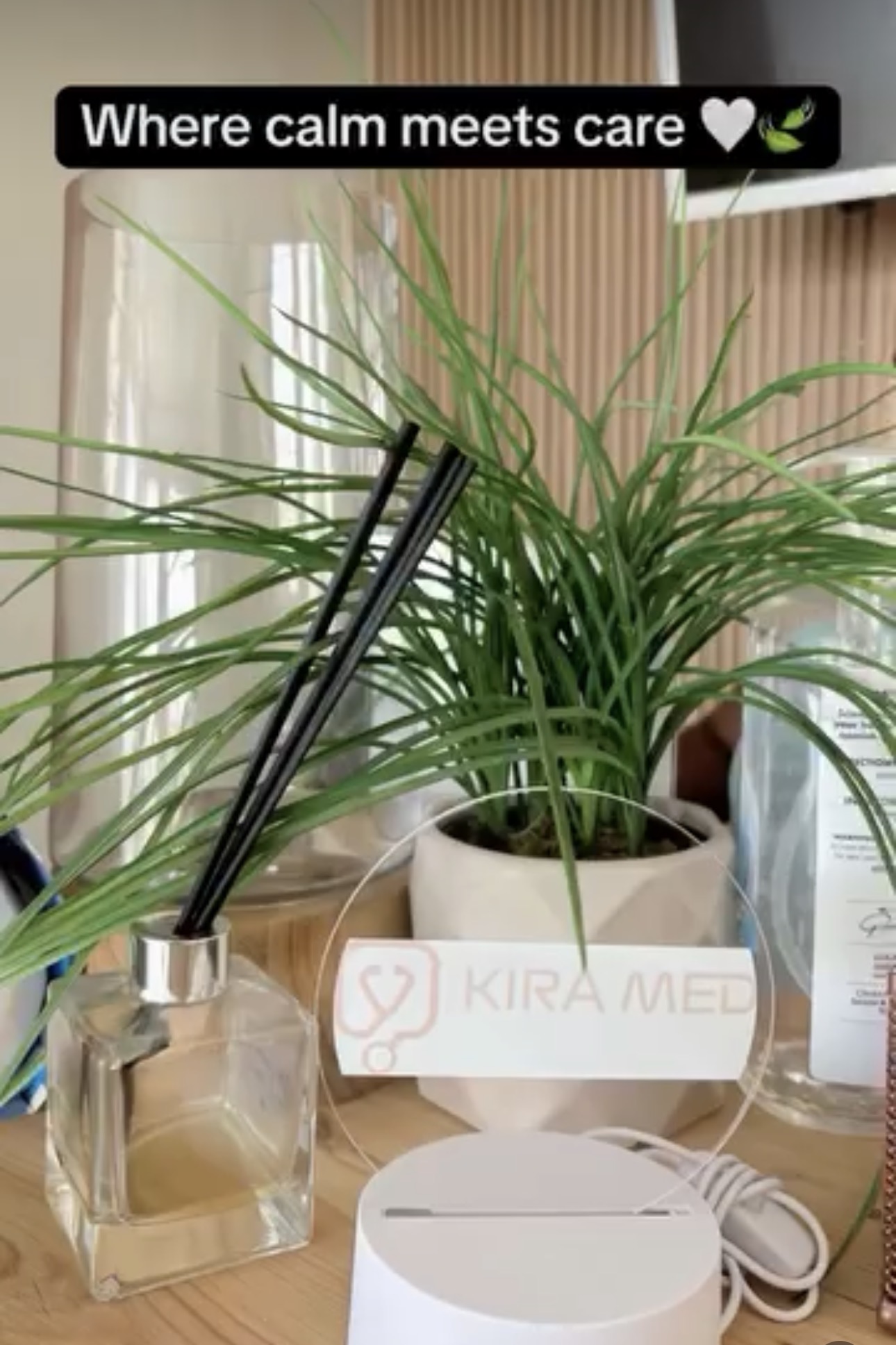 A reed diffuser and plant beside the frosted Kira Med logo sign