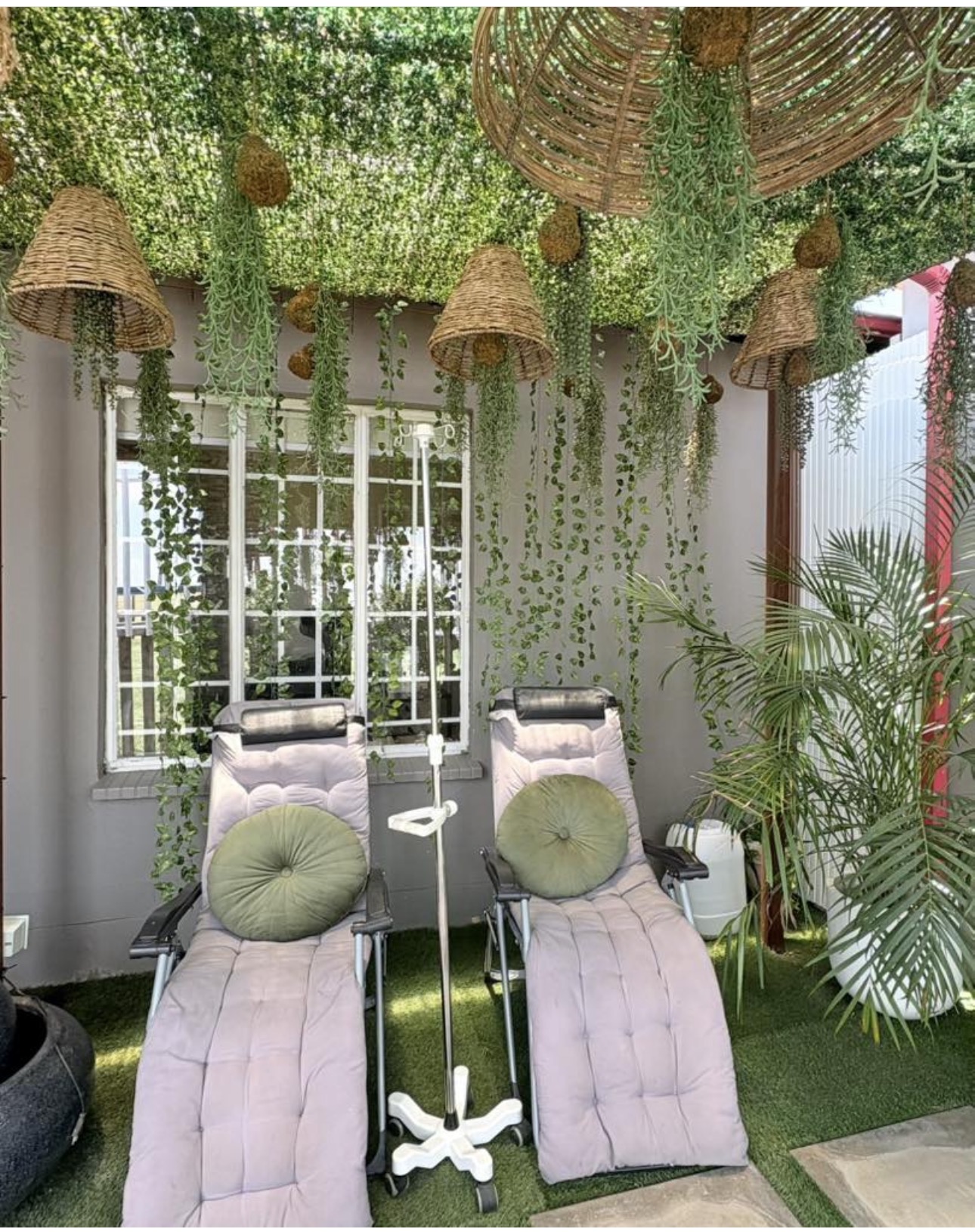 IV drip lounge with plush recliners surrounded by hanging greenery and woven pendant lamps