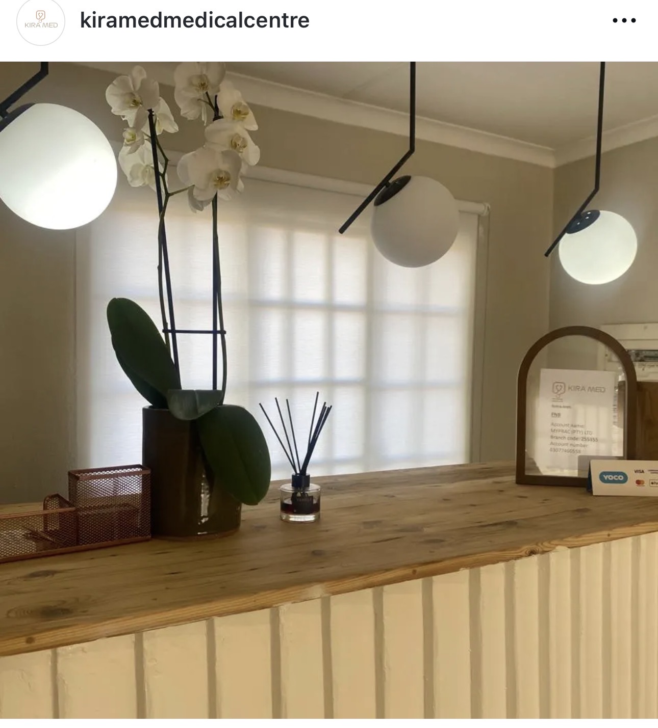 The calm, naturally lit Kira Med reception with a wooden desk, orchids and soft globe lighting